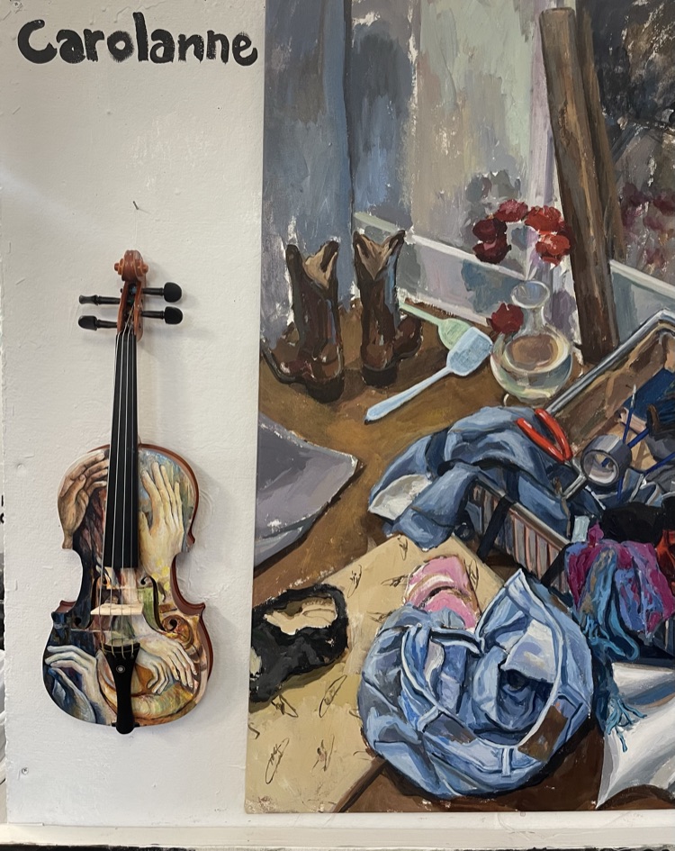 Painted violin hanging beside a still life painting
