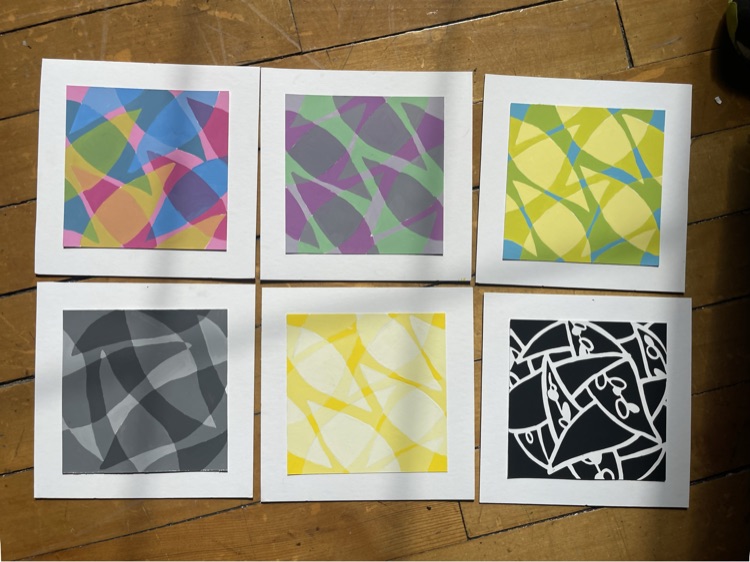 Six screen prints laid on a wooden floor